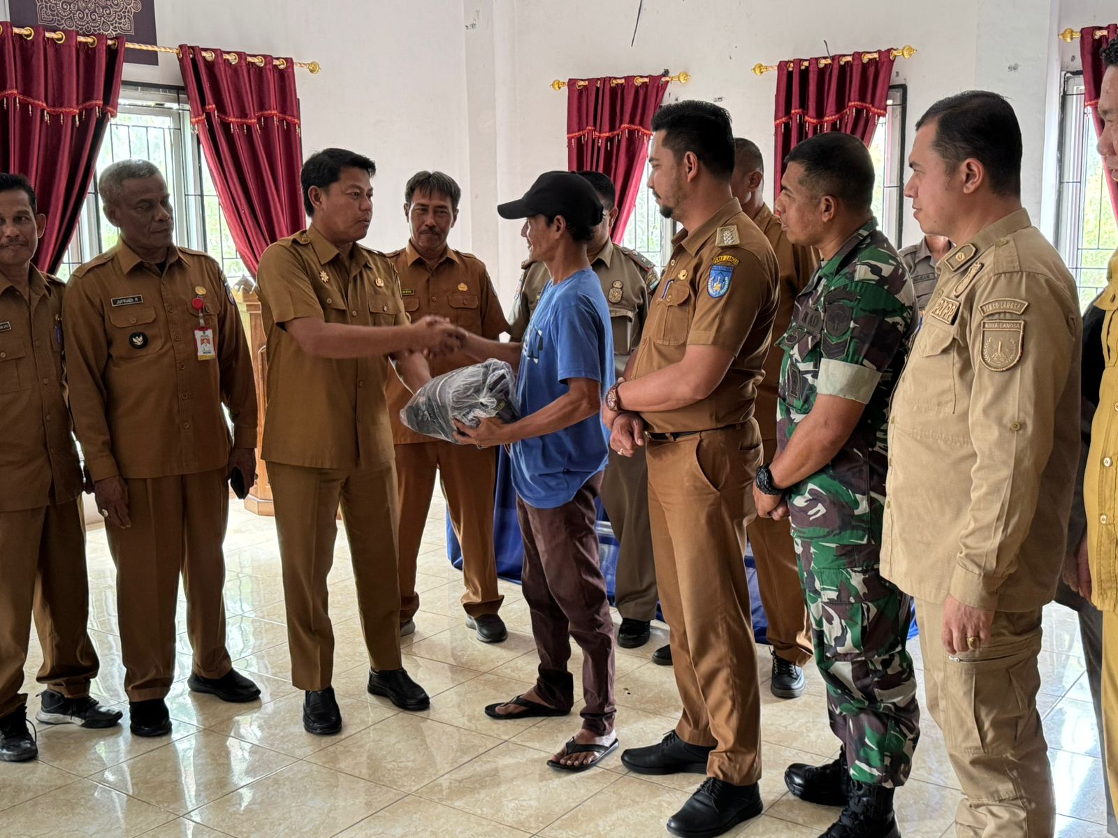 Pj. Sekretaris Daerah Kota Langsa Menyerahkan Perlengkapan dan Atribut kepada Seluruh Anggota Satlinmas PAM TPS Dalam Wilayah Kecamatan Langsa Barat.